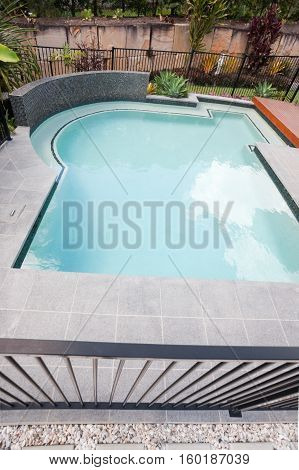 Modern swimming pool with a top of the fence and waterside covered with a garden in a luxury house