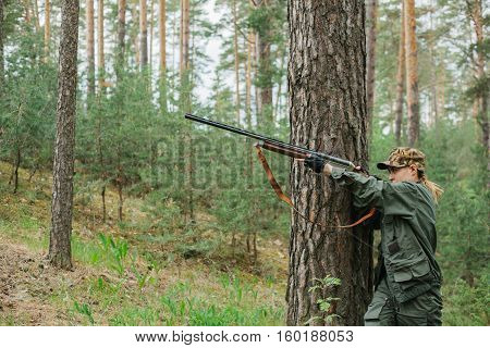 Woman hunter with a gun. Hunting in the woods.