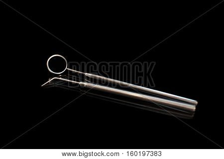 Dental mirror and dental sonde. Image isolated on black background.