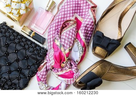 Flat lay. Ladies accessories. Night clutch purse lip stick women perfume high heel shoes and fashion scarf on white background. Christmasgift for her concept.
