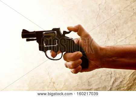 Silhouette of a mans hand with a handgun in brown
