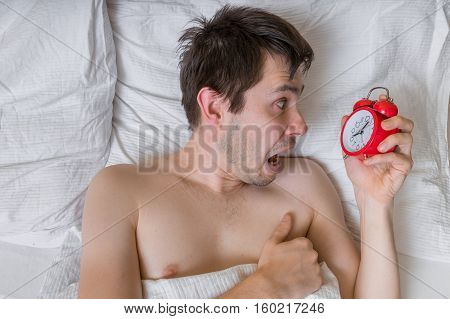 Oversleep Concept. Young Stressed Man Is Waking Up And Is Shoked