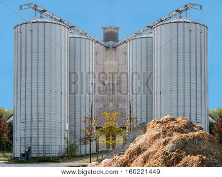 Modern biogas plant of an animal farm. Renewable energy production from biomass. In the foreground a dunghill.