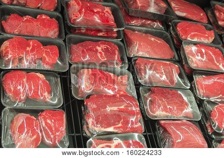 Different types of raw meat in plastic boxes in supermarket