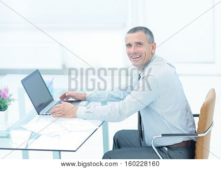 successful smiling businessman working on laptop at Desk in offi