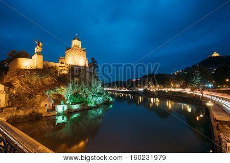 Night Evening Illuminated View Of The Metekhi Church And The Equestrian Statue Of King Vakhtang Gorgasali On The Metekhi Cliff In Old Historic District Of Tbilisi Georgia. Blue Hour. Blue Evening Sky.