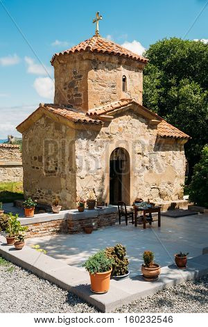 Mtskheta, Georgia. The View Of Ancient Tiny Stone Church Of St. Nina With Green Churchyard At Samtavro Monastery Complex Area In Sunny Day Under Blue Sky.