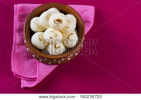 Indian Sweet - Rasgulla, Famous Bengali sweet in clay bowl with napkin on pink background