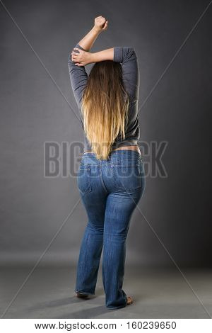 Plus size model in blue jeans xxl woman on gray studio background full length