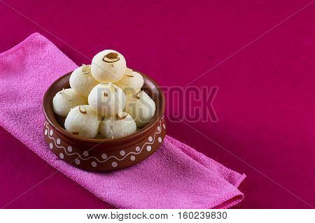 Indian Sweet - Rasgulla, Famous Bengali sweet in clay bowl with napkin on pink background