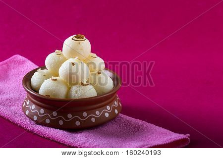 Indian Sweet - Rasgulla, Famous Bengali sweet in clay bowl with napkin on pink background