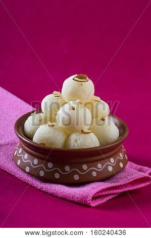 Indian Sweet - Rasgulla, Famous Bengali sweet in clay bowl with napkin on pink background