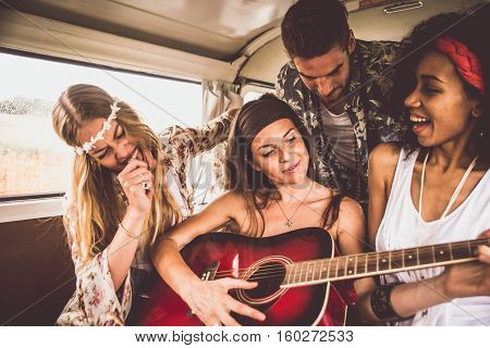 Hippie friends driving on a minivan and playing guitar