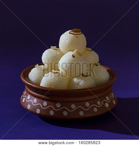 Indian Sweet or Dessert - Rasgulla, Famous Bengali sweet in clay bowl on blue background