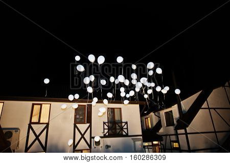 Wedding balloons with light inside on air at night wedding ceremony.
