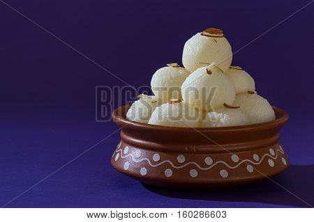 Indian Sweet or Dessert - Rasgulla, Famous Bengali sweet in clay bowl on blue background