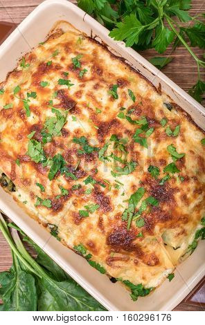Chicken lasagna and white cheese on a wooden table .