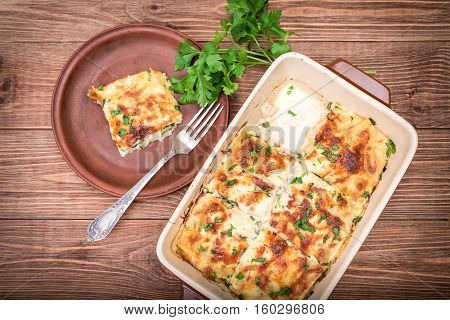 Chicken lasagna and white cheese on a wooden table .