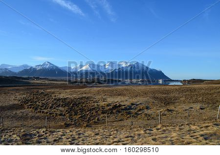 Fishing village and town at the base of a snow covered mountains in Iceland.
