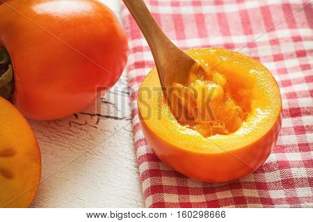 Japanese persimmon (Diospyros kaki) on white rustic wooden background