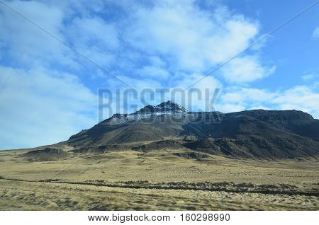 Fluffy white clouds and blue skies over the mountains in Iceland.