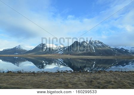 Rhyolite mountains reflecting in a large pool of water.