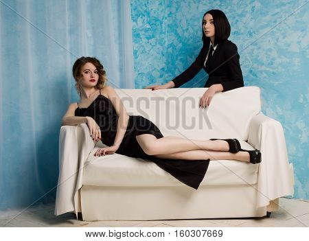 Two Fashionable Girls Sitting On The Armchair