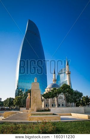BAKU, AZERBAIJAN - OCT 4, 2016: Mosque of the Martyrs (Sehidler Mescidi Mosque, Turkish Mosque) with the Flame Towers skyscraper in the background in Baku on Oct 4, 2016, Azerbaijan, at sunset. 