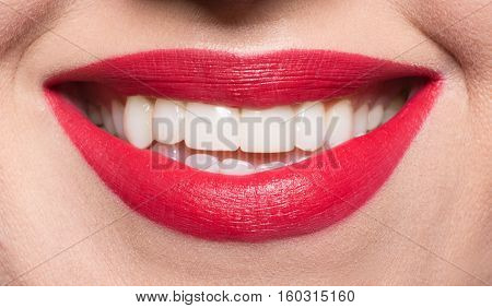 Closeup picture of beautiful model woman's face. Pretty lady looking at camera, smiling abd touching her brown hair.