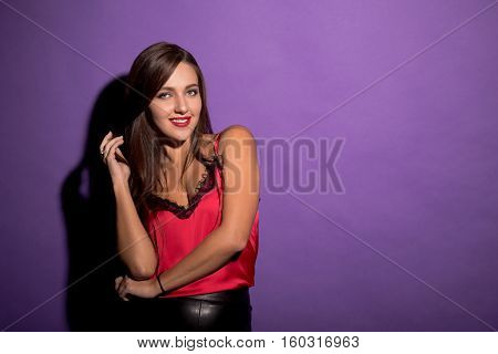 Beautiful model woman demonstrating her gorgeous brown hair while posing for photographer isolated on violet background in studio.