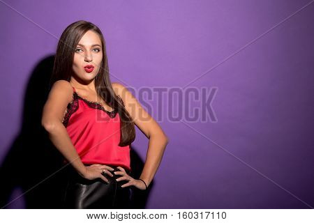Beautiful model woman posing with her hands on hips in studio. Brown haired young lady looking at camera. Fahion magazine concept.