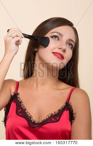 Portrait if happy smiling young model woman usinf brush and powder for doing makeup isolated on white background. Cosmetics concept.