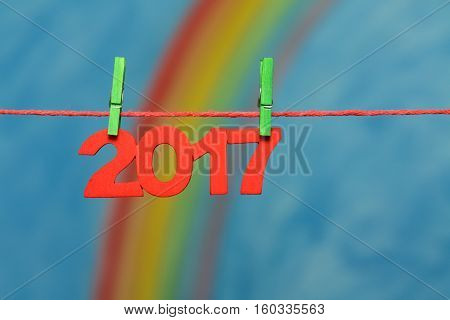 Red 2017 New Year's Eve numbers with a colorful rainbow and blue sky background sky to illustrate the concept of new beginnings and resolutions.