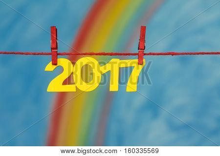Yellow 2017 New Year's Eve numbers with a colorful rainbow and blue sky background sky to illustrate the concept of new beginnings and resolutions.