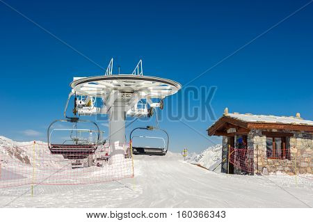 Ski lift station in mountains at winter. Alpine winter mountain landscape. French Alps covered with snow in sunny day. Val-d'Isere, Alps, France