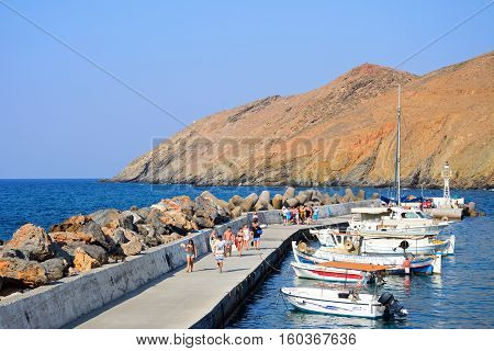 PANORMOS, CRETE - SEPTEMBER 15, 2016 - Traditional Greek fishing boats moored in the harbour with tourists walking along the quayside Panormos Crete Greece Europe, September 15, 2016.
