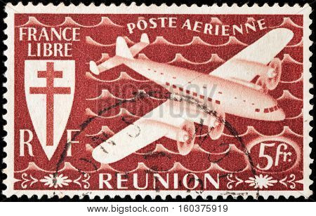 LUGA RUSSIA - NOVEMBER 29 2016: A stamp printed by REUNION shows airplane and Croix de Lorraine. Reunion is an island and region of France in the Indian Ocean circa 1944.