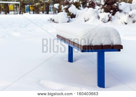 Wooden bench covered by snow in winter day