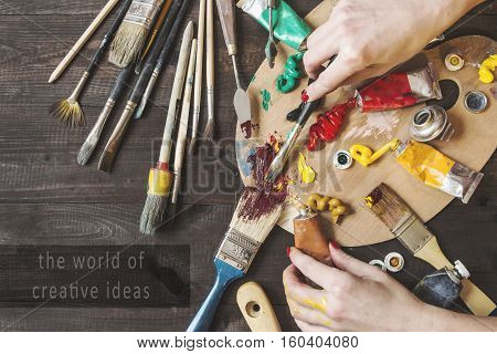 woman's hand with oil paints and kistyai with inscription world of creative ideas