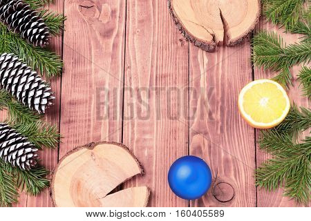 Christmas New Year composition with tangerines, cones, nuts, wicker basket and fir branches in rustic style on old wooden background, selective focus, Background new year, fir, gift, cones, orange, blue ball, red background