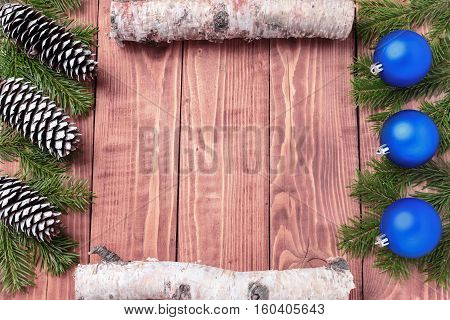Christmas New Year composition with tangerines, cones, nuts, wicker basket and fir branches in rustic style on old wooden background, selective focus, Background new year, fir, gift, cones, orange, blue ball, red background