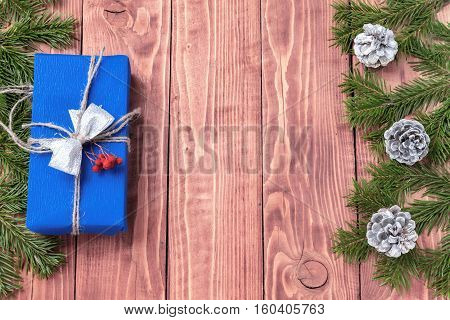 Christmas New Year composition with tangerines, cones, nuts, wicker basket and fir branches in rustic style on old wooden background, selective focus, Background new year, fir, gift, cones, orange, blue ball, red background
