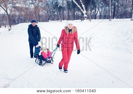Young Family Running Through Snow With Sled