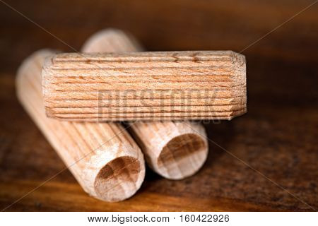 Macro photography of three wooden dowels on a dark wooden work table