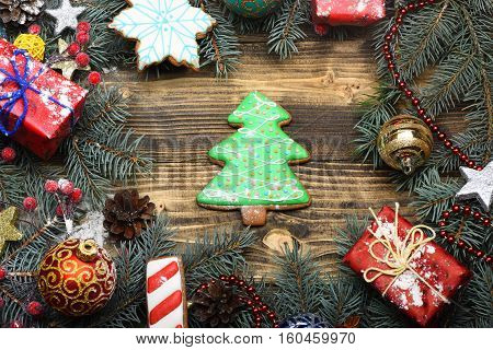 green firry christmas wreath decorative with silver golden stars colorful presents with xmas balls and candy canes on middle on brown vintage wooden background