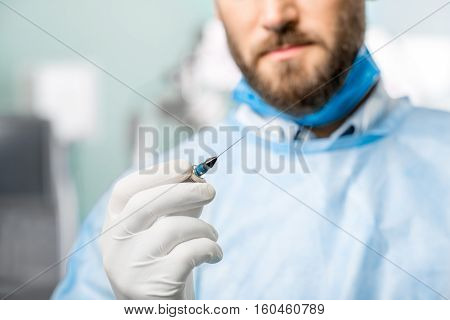 Surgeon holding small surgical scissors for eye operation in the operating room. Image with small deph of field focused on hands and scissors