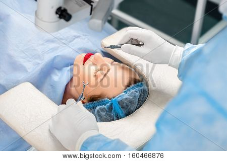 Surgion operating eye of female patient with surgical tools in the operating room