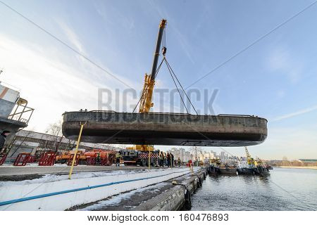 MOSCOW, RUSSIA - NOVEMBER 11, 2016: State Unitary Enterprise Mosvodostok performs recovery vessels on coastal winter parking. Easy river barge suspended in the automobile crane.