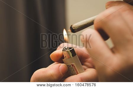 Person lighting a joint, spliff, or cigarette with a butane lighter.