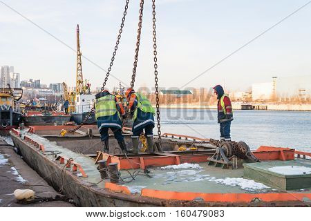 MOSCOW, RUSSIA - NOVEMBER 11, 2016: State Unitary Enterprise Mosvodostok performs recovery vessels on coastal winter parking. Workers slingers hooked to the vehicle chain slings.